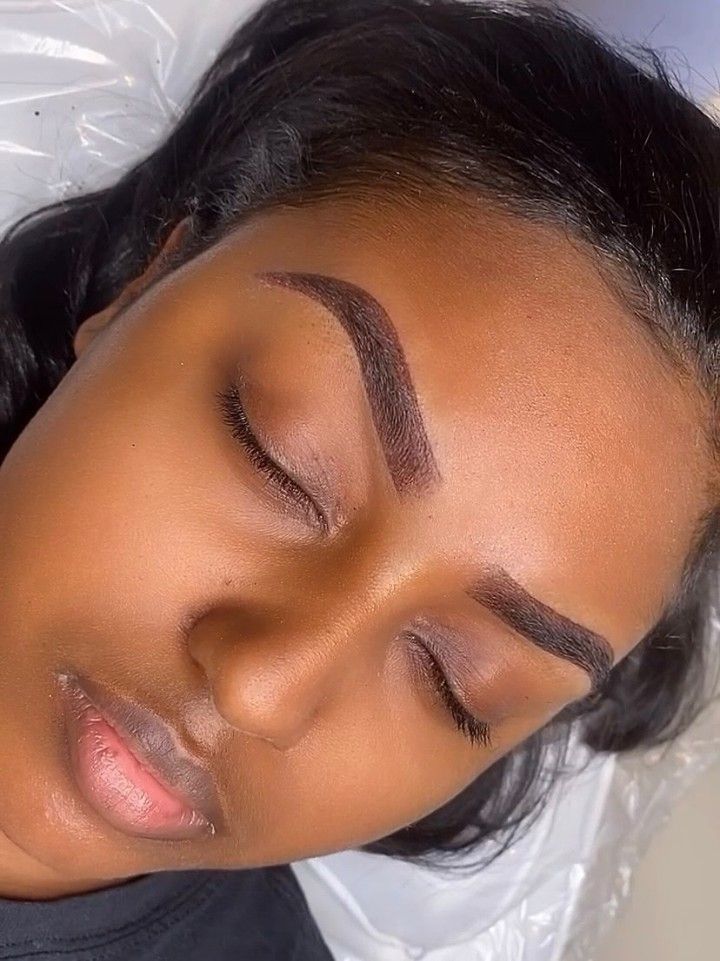 A client with freshly shaped brows, eyes closed on the treatment bed